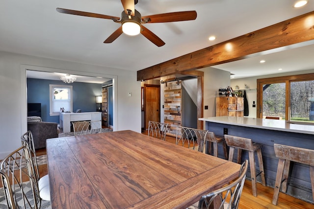 dining space featuring ceiling fan with notable chandelier, a barn door, and light wood-type flooring