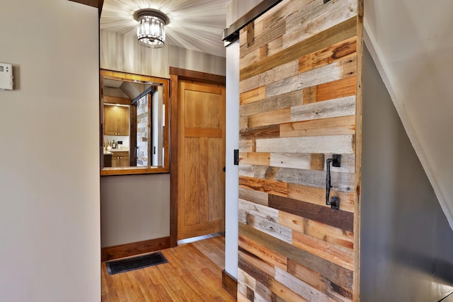 interior space with wood-type flooring, a notable chandelier, and wood walls