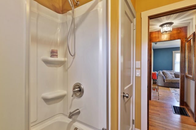 bathroom featuring hardwood / wood-style flooring and  shower combination