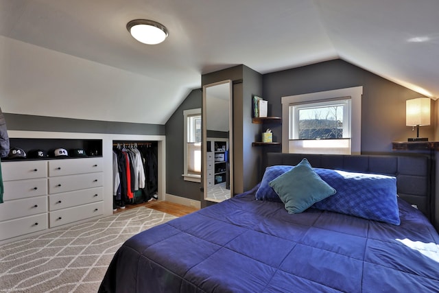 bedroom with light wood-type flooring, a closet, and lofted ceiling