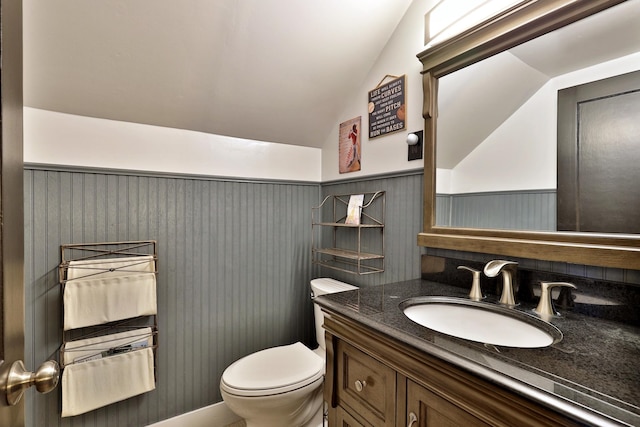 bathroom featuring vanity, toilet, and lofted ceiling