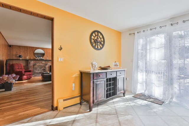 bar with a fireplace, light hardwood / wood-style flooring, wooden walls, and a baseboard heating unit