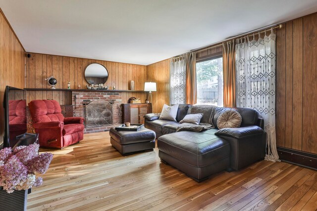 living room with a brick fireplace, wood walls, and light hardwood / wood-style flooring