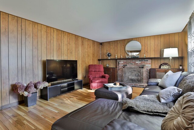 living room featuring wooden walls, a fireplace, and light hardwood / wood-style floors