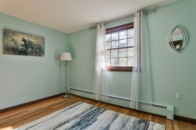 spare room with hardwood / wood-style floors and a baseboard radiator