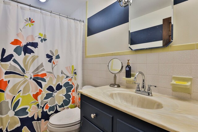 bathroom featuring vanity, tile walls, and toilet