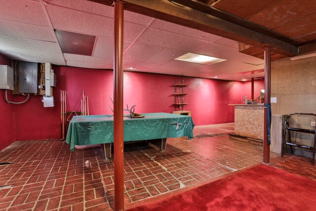 basement with electric panel, a paneled ceiling, and billiards