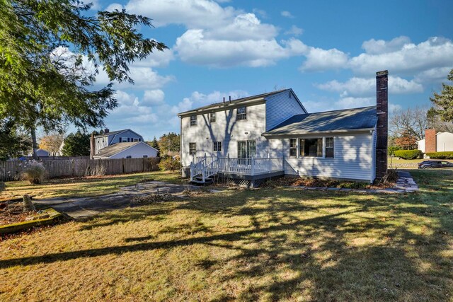 back of house featuring a lawn and a deck