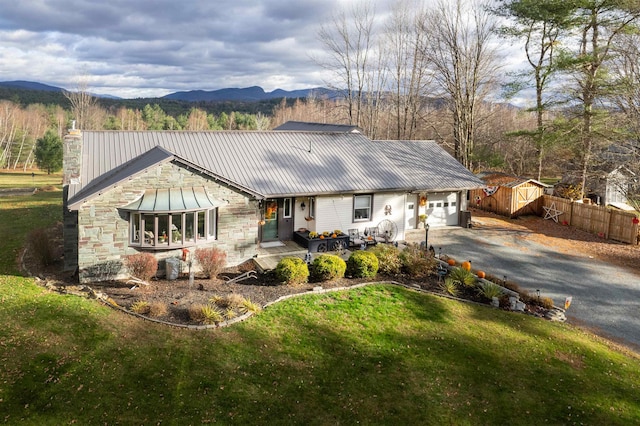 view of front of home with a mountain view, a garage, a storage shed, and a front lawn