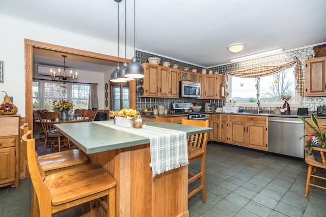 kitchen with appliances with stainless steel finishes, a center island, decorative light fixtures, and a healthy amount of sunlight