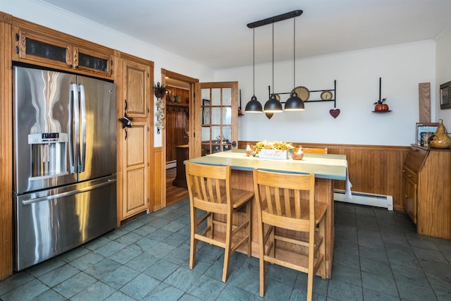 kitchen with a center island, baseboard heating, stainless steel fridge, decorative light fixtures, and a breakfast bar