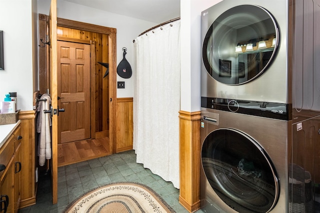 clothes washing area featuring stacked washer / drying machine and wooden walls