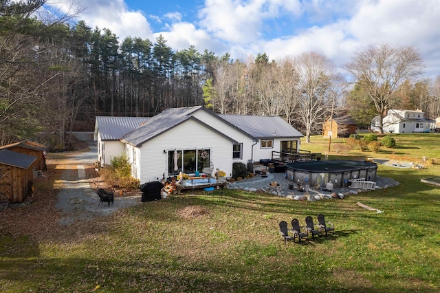 back of house featuring a swimming pool side deck, a storage shed, and a lawn