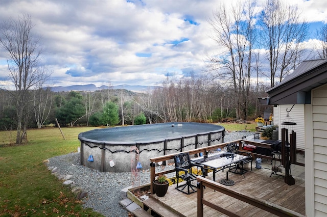 wooden deck featuring a lawn, a mountain view, and a covered pool