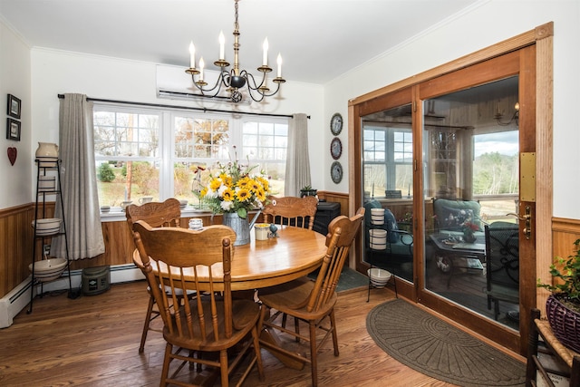 dining area featuring ornamental molding, baseboard heating, an inviting chandelier, dark hardwood / wood-style floors, and wood walls