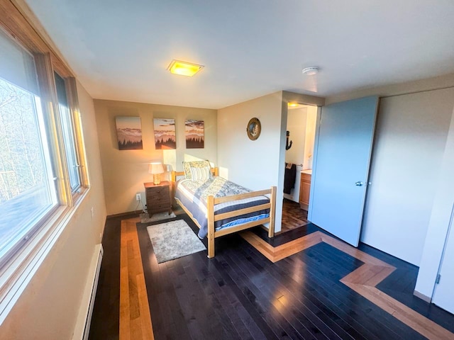 bedroom with dark hardwood / wood-style flooring and a baseboard heating unit