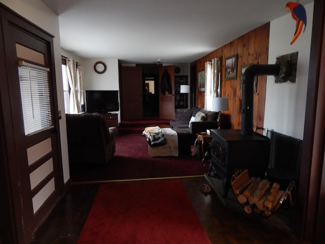 living room with a wood stove and wooden walls