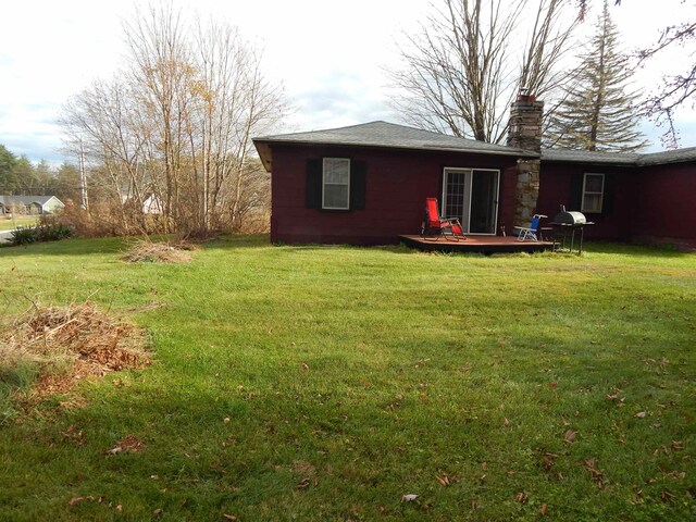 rear view of property featuring a wooden deck and a yard