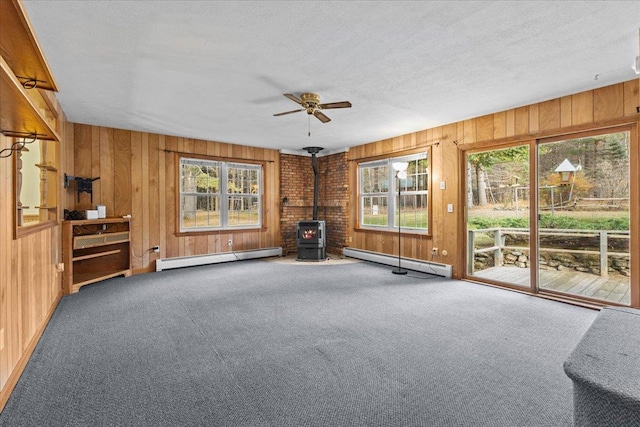 interior space with a wood stove, plenty of natural light, and a baseboard radiator