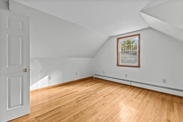 additional living space featuring lofted ceiling, light hardwood / wood-style flooring, and a baseboard heating unit