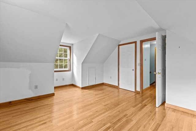 bonus room with light wood-type flooring and vaulted ceiling