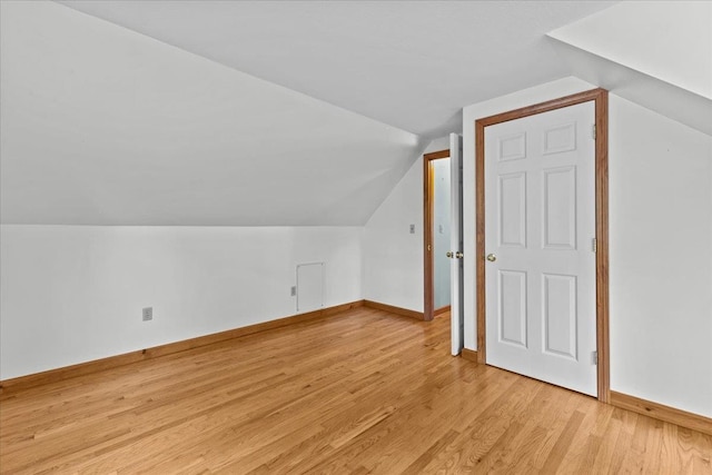 additional living space featuring light wood-type flooring and lofted ceiling