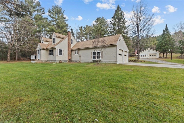 rear view of house with a lawn, a garage, and an outbuilding