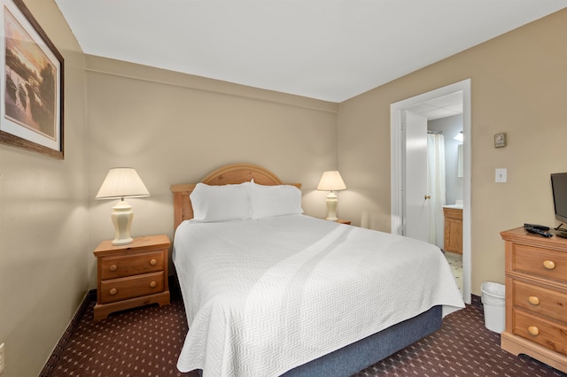 bedroom featuring dark colored carpet and ensuite bath