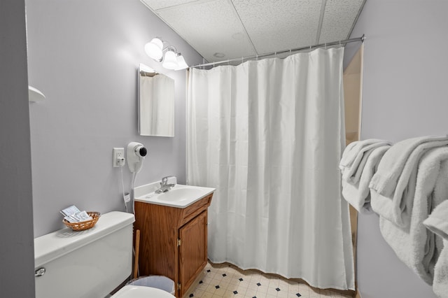 bathroom with vanity, a drop ceiling, toilet, and walk in shower