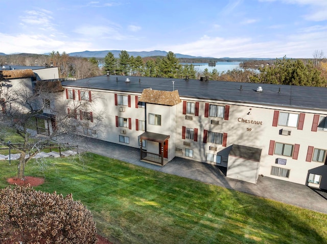 rear view of property with a lawn and a water and mountain view