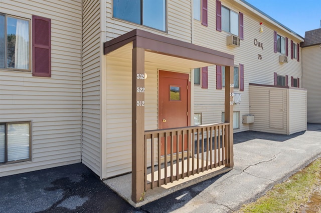 view of exterior entry with cooling unit and a wall unit AC