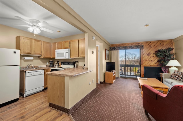 kitchen with kitchen peninsula, light brown cabinetry, light wood-type flooring, white appliances, and wood walls