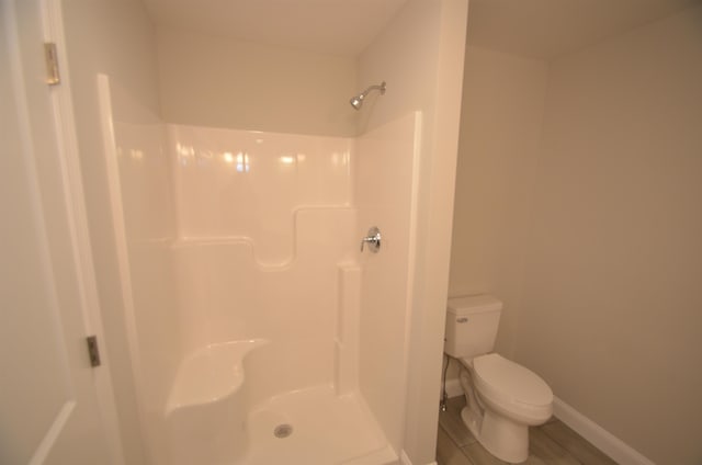 bathroom featuring walk in shower, hardwood / wood-style floors, and toilet