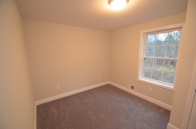 spare room featuring dark colored carpet