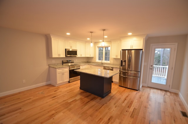 kitchen with decorative light fixtures, stainless steel appliances, a kitchen island, and a healthy amount of sunlight