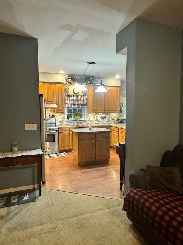 kitchen featuring sink, decorative light fixtures, stainless steel electric stove, decorative backsplash, and a kitchen island