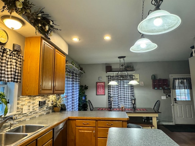 kitchen featuring sink, hanging light fixtures, stainless steel dishwasher, backsplash, and kitchen peninsula