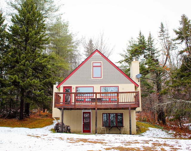 snow covered back of property featuring a deck