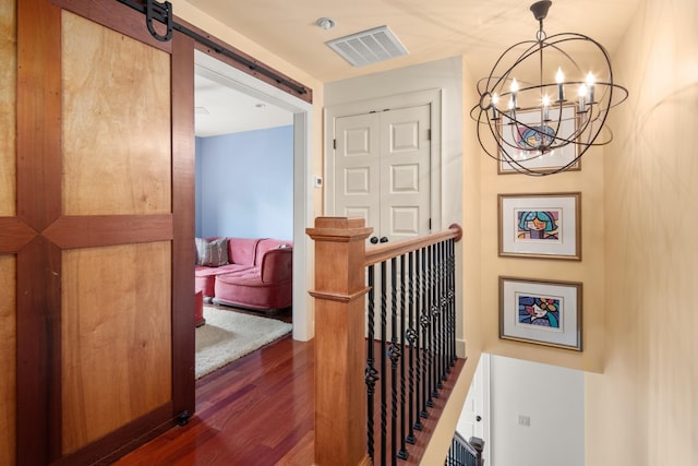 hall featuring dark hardwood / wood-style flooring, a barn door, and an inviting chandelier