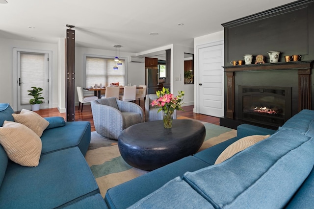 living room with a wall mounted AC and dark wood-type flooring