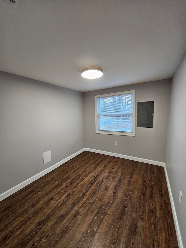 empty room with electric panel and dark hardwood / wood-style flooring