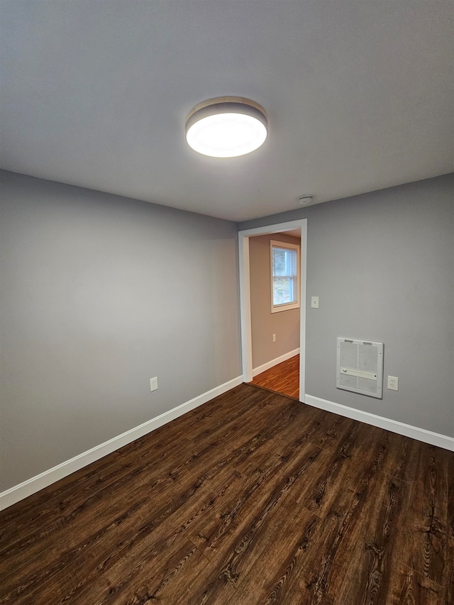 empty room featuring dark hardwood / wood-style floors and heating unit