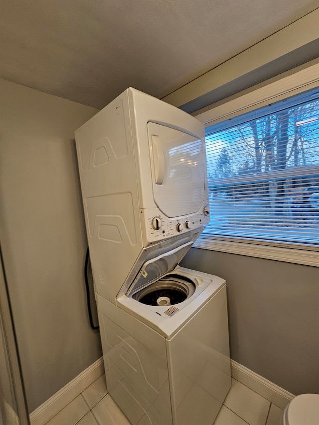 washroom with light tile patterned flooring and stacked washer / drying machine