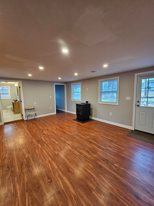 unfurnished living room with wood-type flooring and a wood stove