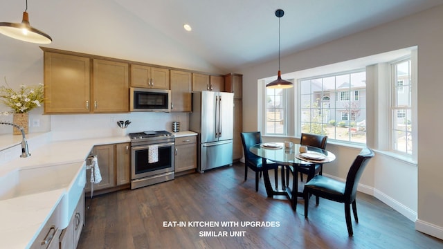 kitchen with stainless steel appliances, pendant lighting, dark wood-type flooring, sink, and lofted ceiling