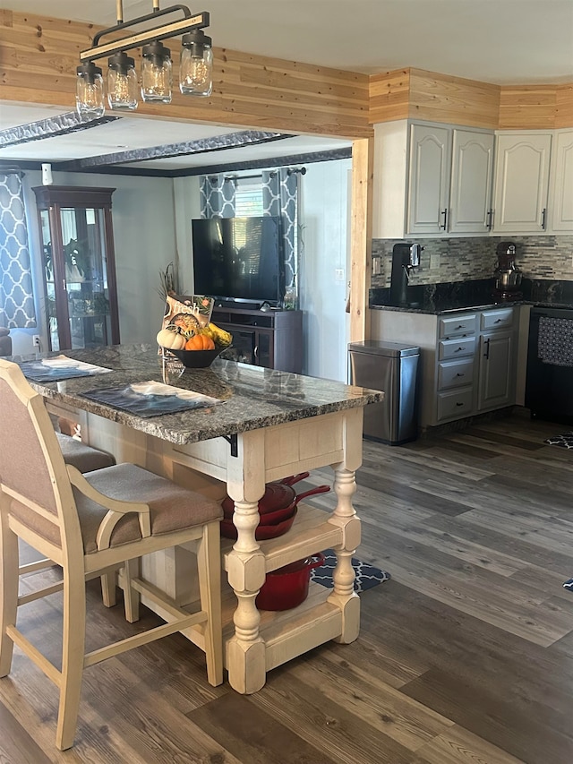 kitchen with decorative backsplash, a kitchen bar, white cabinetry, and dark wood-type flooring