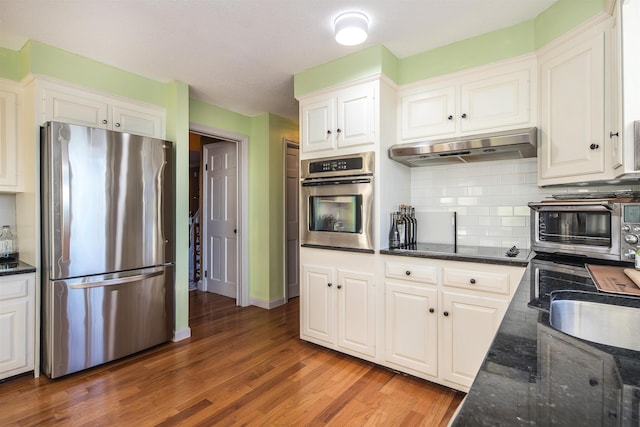 kitchen with dark hardwood / wood-style floors, white cabinetry, appliances with stainless steel finishes, and tasteful backsplash