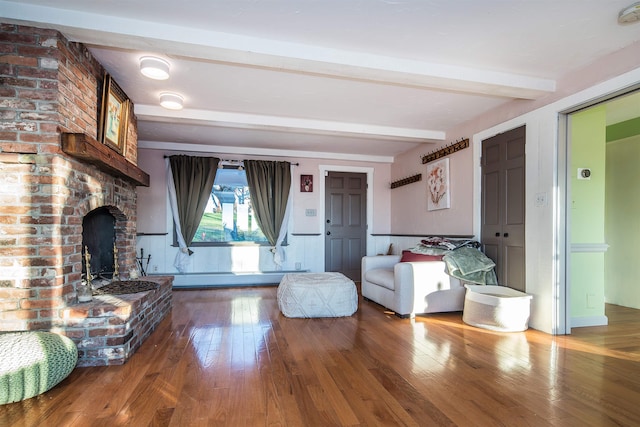 unfurnished living room featuring beam ceiling, a fireplace, hardwood / wood-style floors, and a baseboard radiator