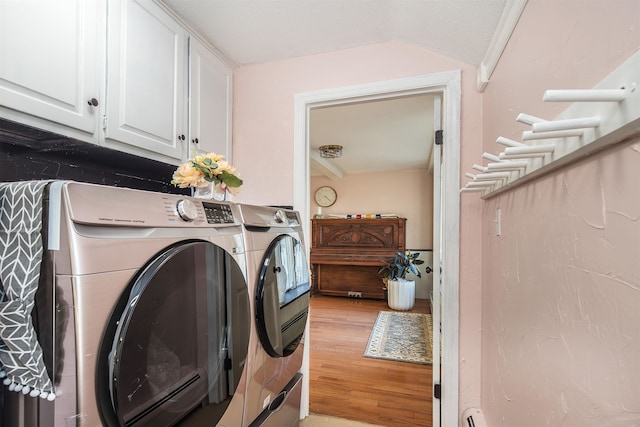 laundry room with washer and dryer, a textured ceiling, light hardwood / wood-style floors, and cabinets