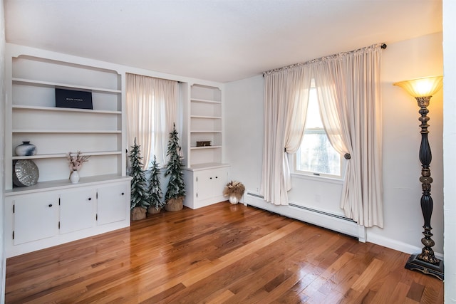 unfurnished living room featuring hardwood / wood-style floors and a baseboard radiator